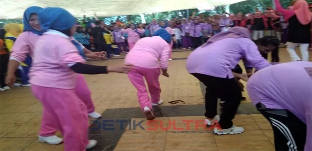 Tampak ibu berlomba memindahkan belut.